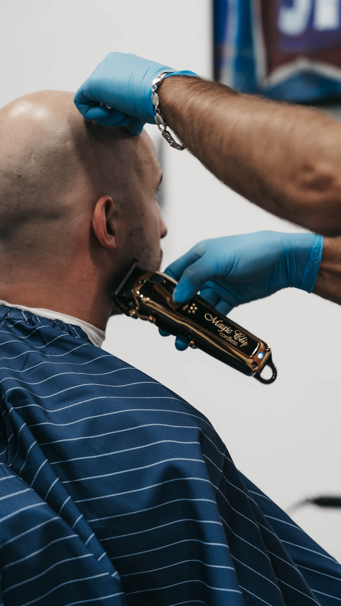 Barber shaving a client with a trimmer, close up shot